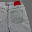 Light blue jeans with rhinestone embellishments on a beige background