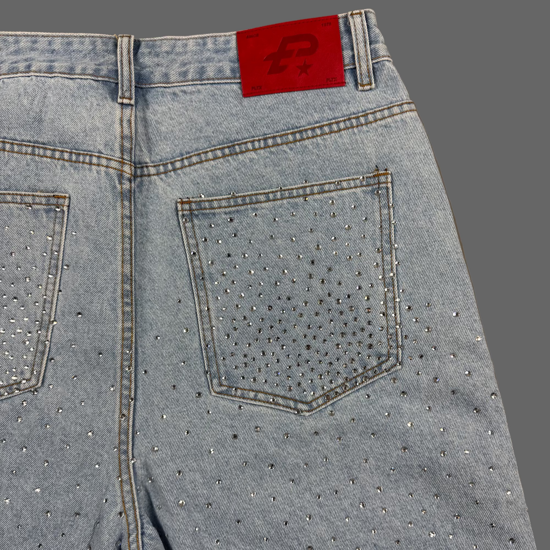 Light blue jeans with rhinestone embellishments on a beige background