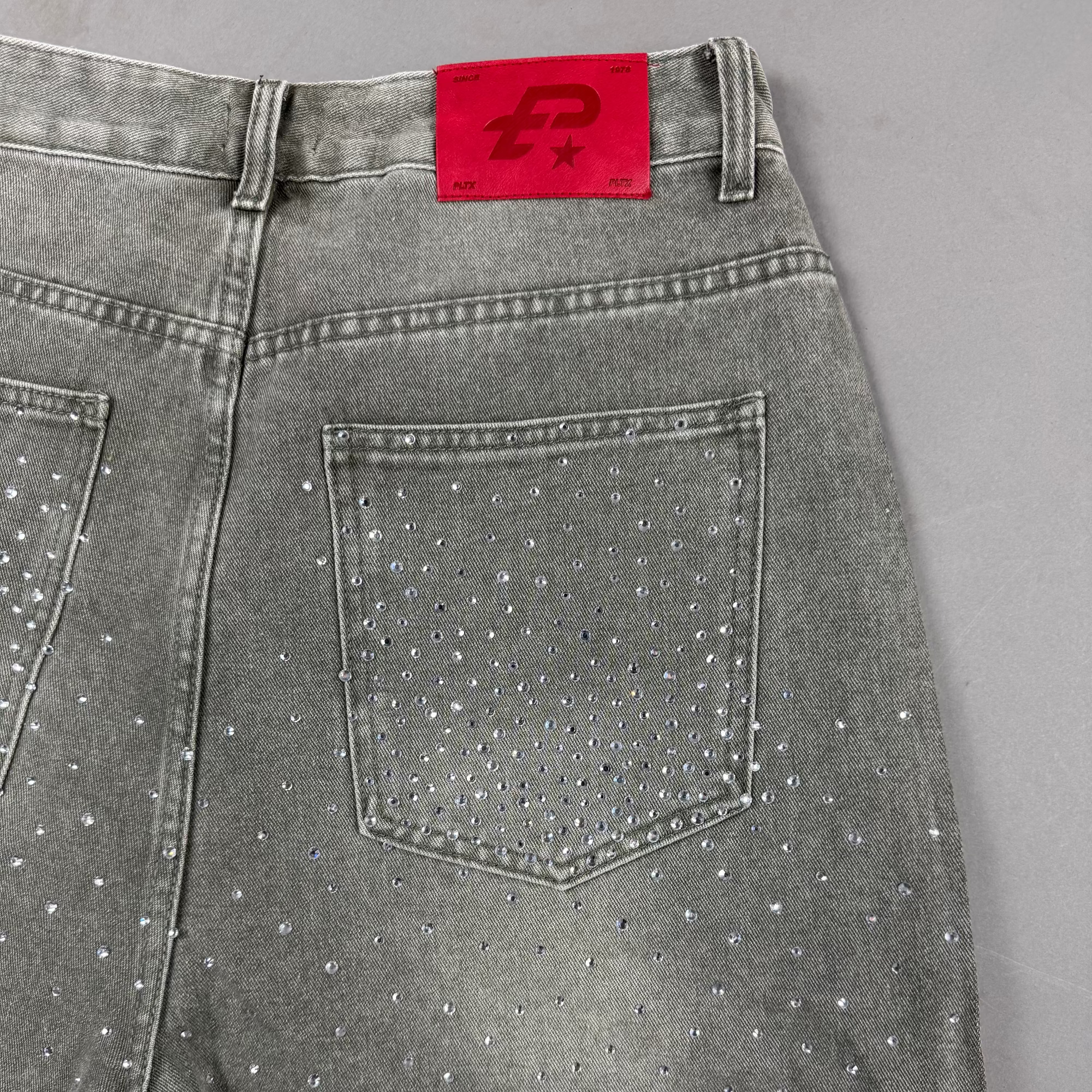 Gray jeans with rhinestone embellishments on a gray background